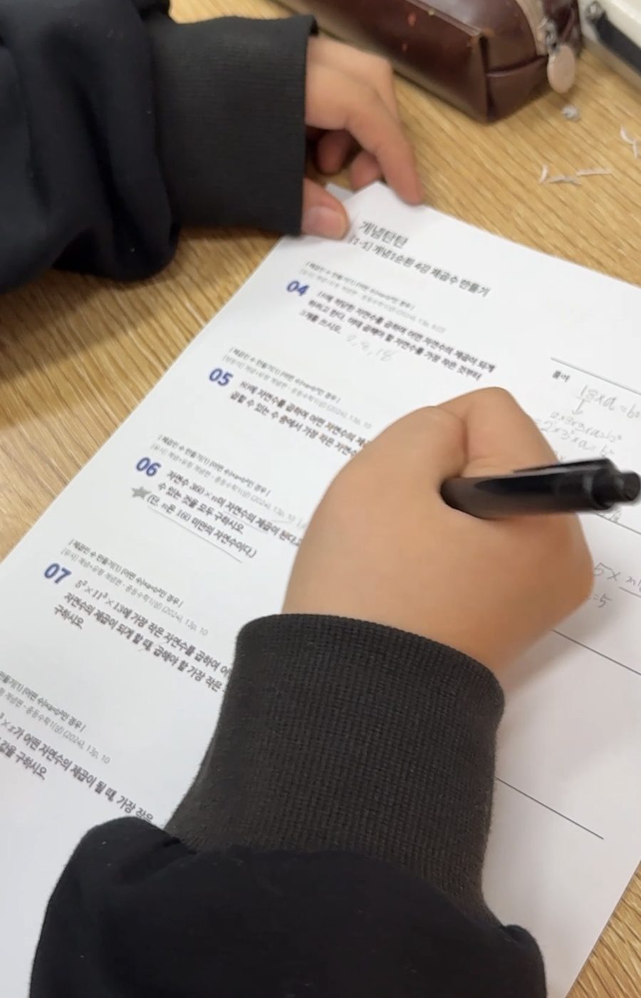 학생이 개념 학습지에 손으로 풀이를 쓰는 모습